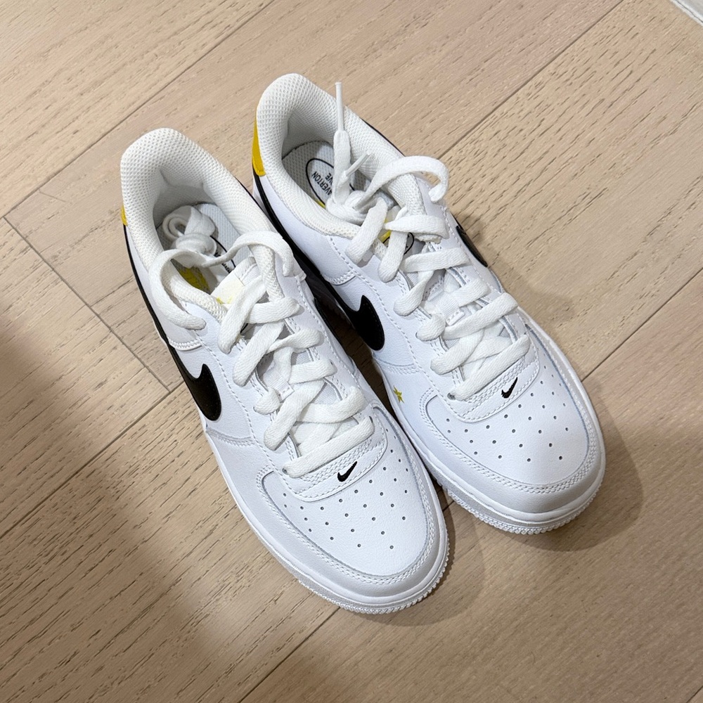 Nike White Low-Top Sneakers with Black Swoosh and Yellow Heel Detail